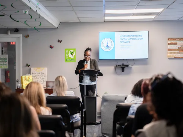 Alumni director Josh Gray leads an educational seminar and supportive group discussion in a modern facility room.