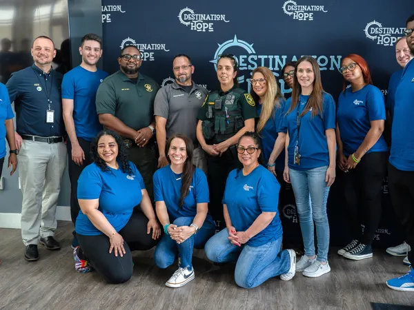 A large, diverse group of Destination Hope staff members and local police officers stand together, highlighting strong community ties.