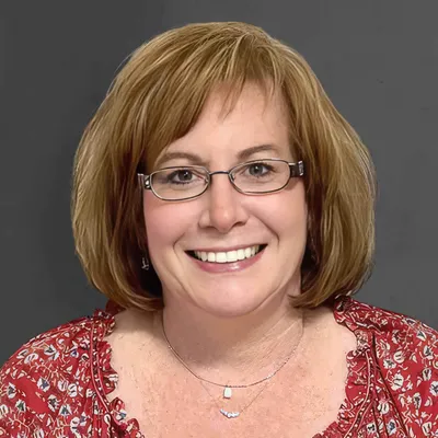 Professional portrait of female medical director and psychiatrist smiling in clinical office setting.