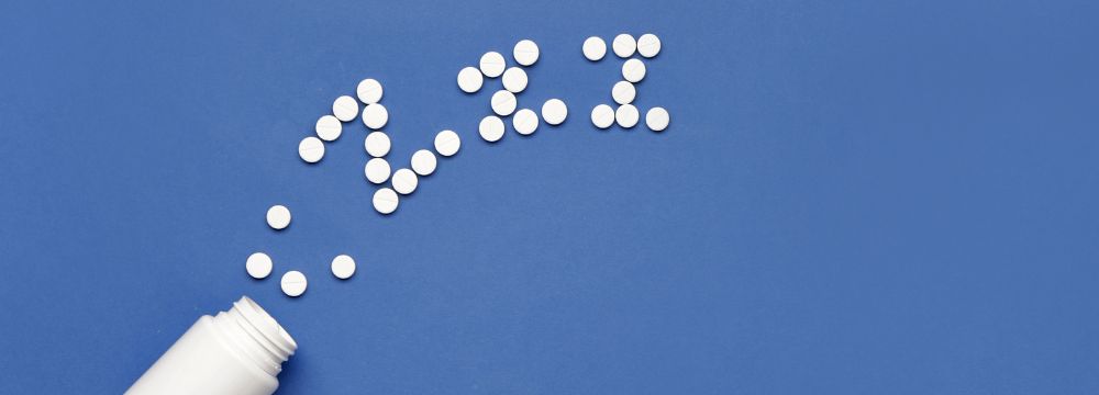 White pills spill out of a bottle in the shape of z's against a blue background