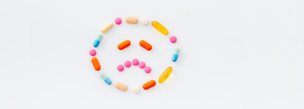 Pills arranged in the shape of a frowning face, illustrating how substance use complicates an untreated mental health condition