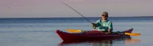 Man fishing in the ocean inside a canoe