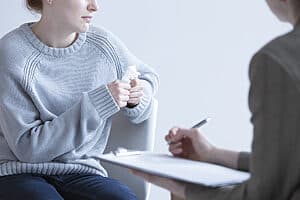 Crying woman talking to psychologist during therapy session.