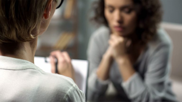 Woman talking to therapist while taking notes