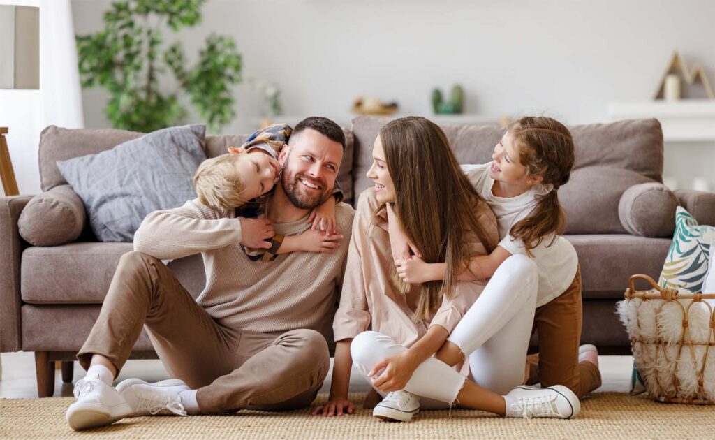 Smiling parents on the floor with children happily climbing on top of them