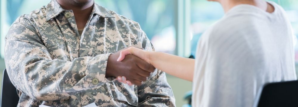 Veteran shakes hands after successfully completing mental health and addiction treatment and getting back on his feet