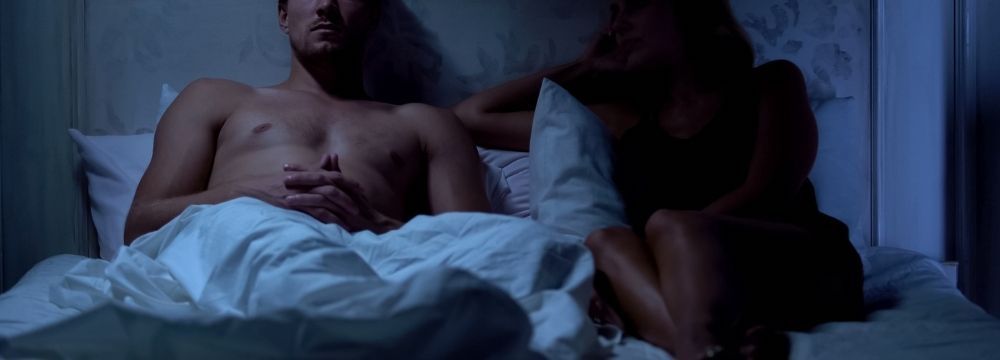 Couple sits in dark bedroom navigating the physical and emotion effects of substance abuse on their sex life