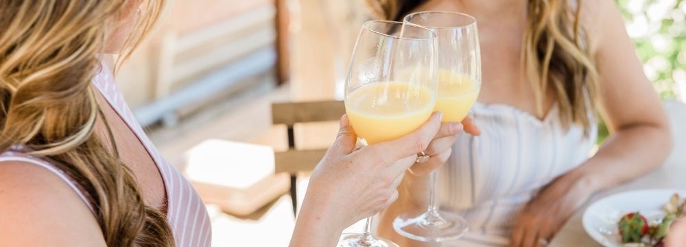 Woman peer pressures her friend to drink more than she would like to over brunch