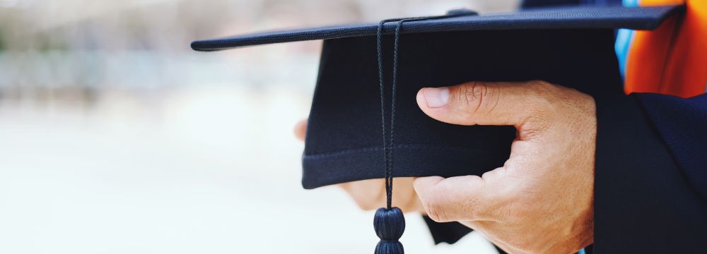 Teacher holds graduation cap for student prepared to graduate high school after completing a successful residential treatment program for major depression and anxiety and getting back on track
